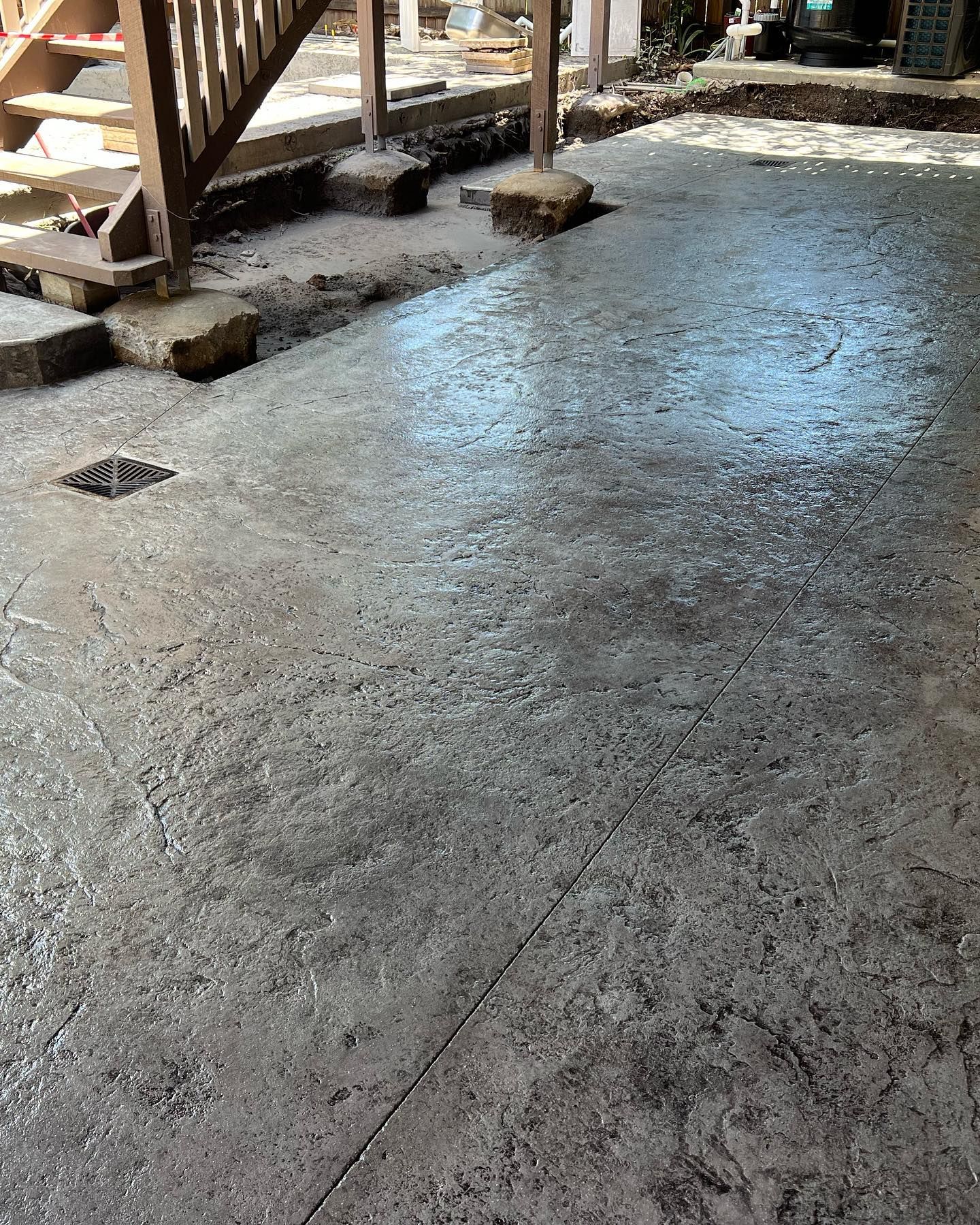 Freshly poured concrete slab under stairs with a small drain opening outdoors Freshly poured concrete slab under stairs with a small drain opening outdoors