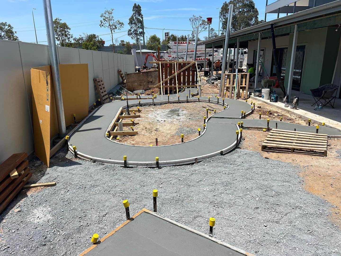Construction site with curved concrete paths and gravel in a landscaped yard area