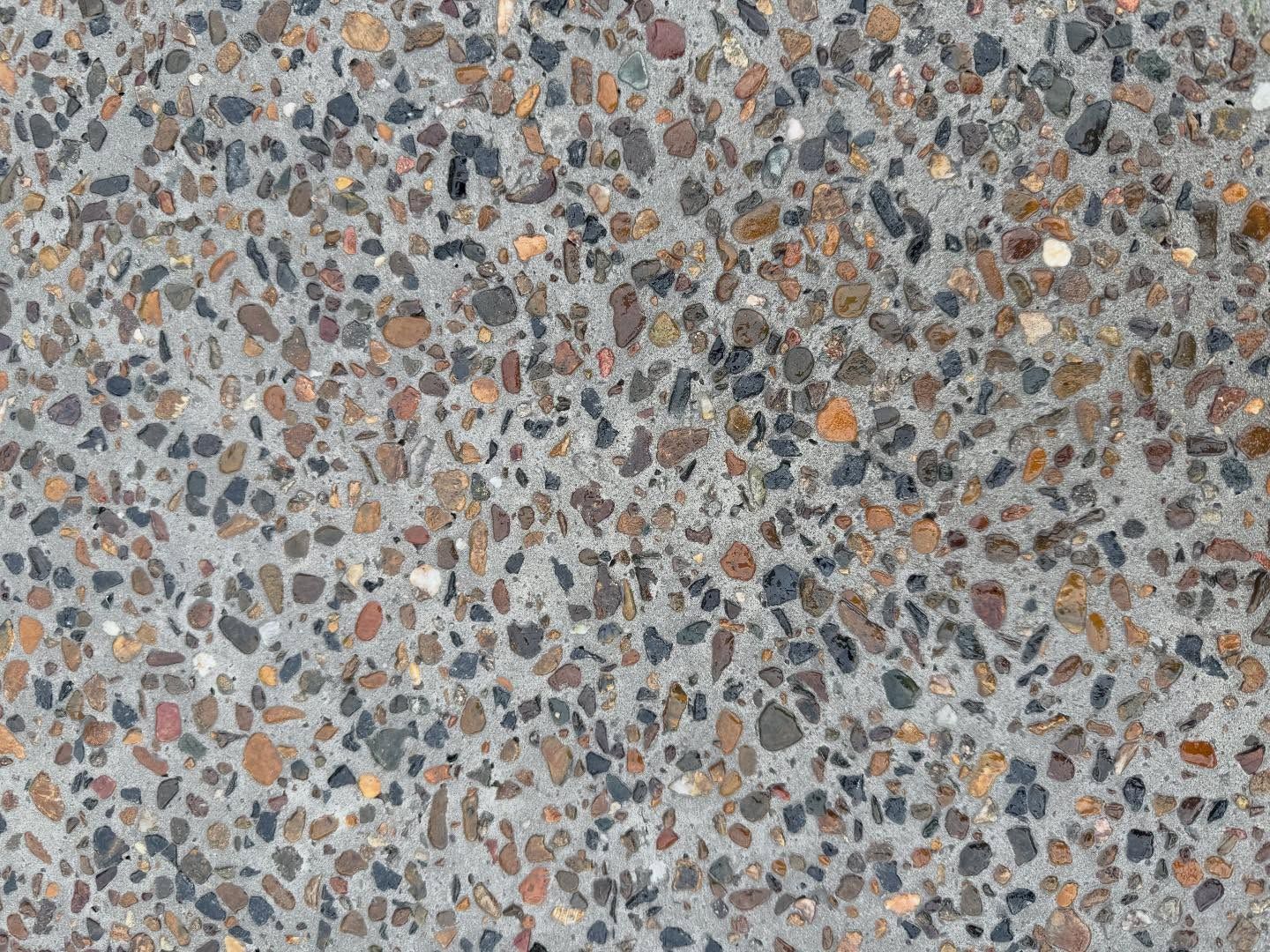Close-up of speckled gray concrete with multicolored aggregate stones