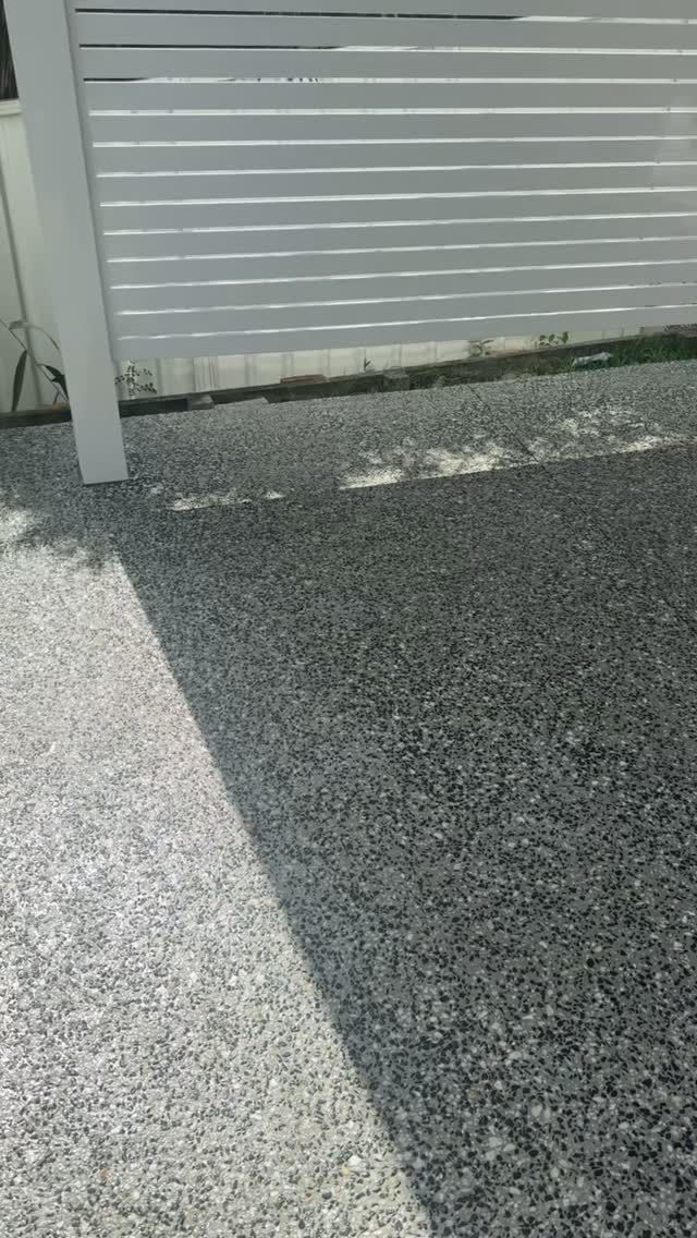 Gravel driveway beside a white fence, with a diagonal shadow across the ground.