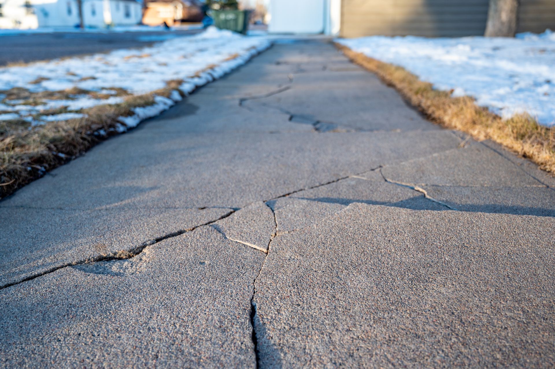 Cracked sidewalk stretching into the distance with snow on both sides