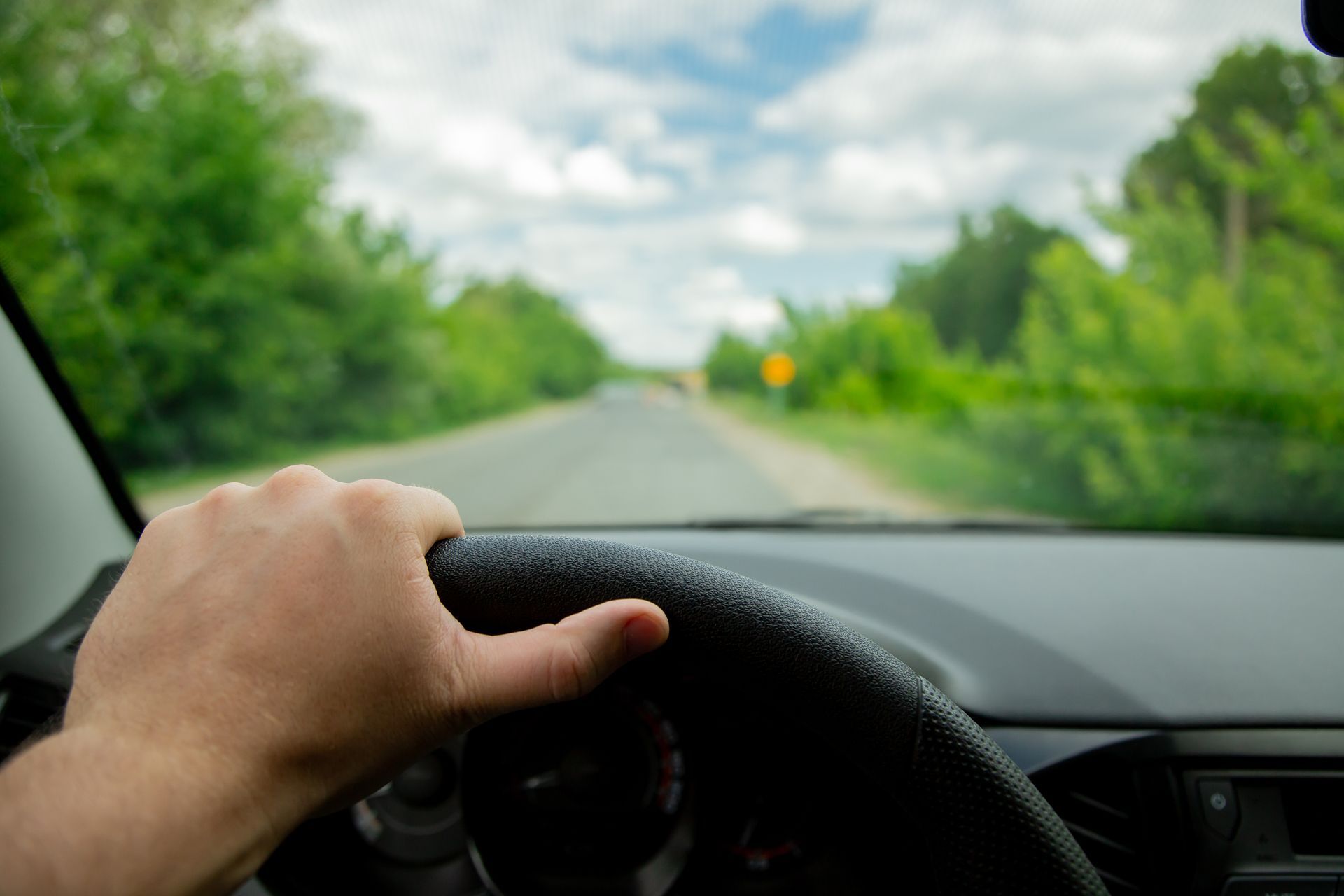 Driver's view of a rural Northwest Indiana road, hand on the steering wheel