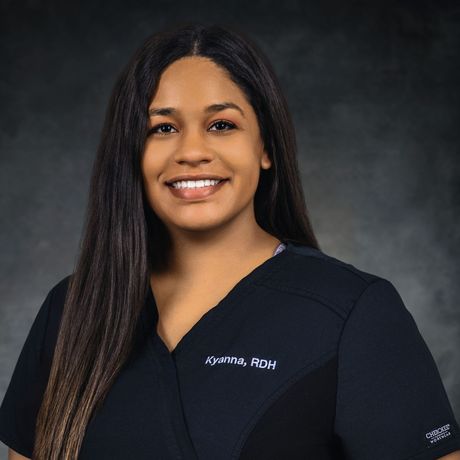 Woman in black scrubs smiles;
