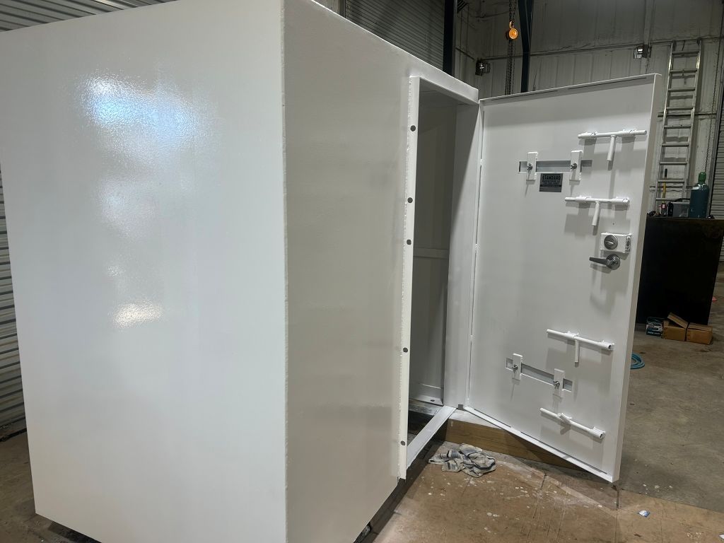 White metal storm shelter with the door open in a warehouse setting