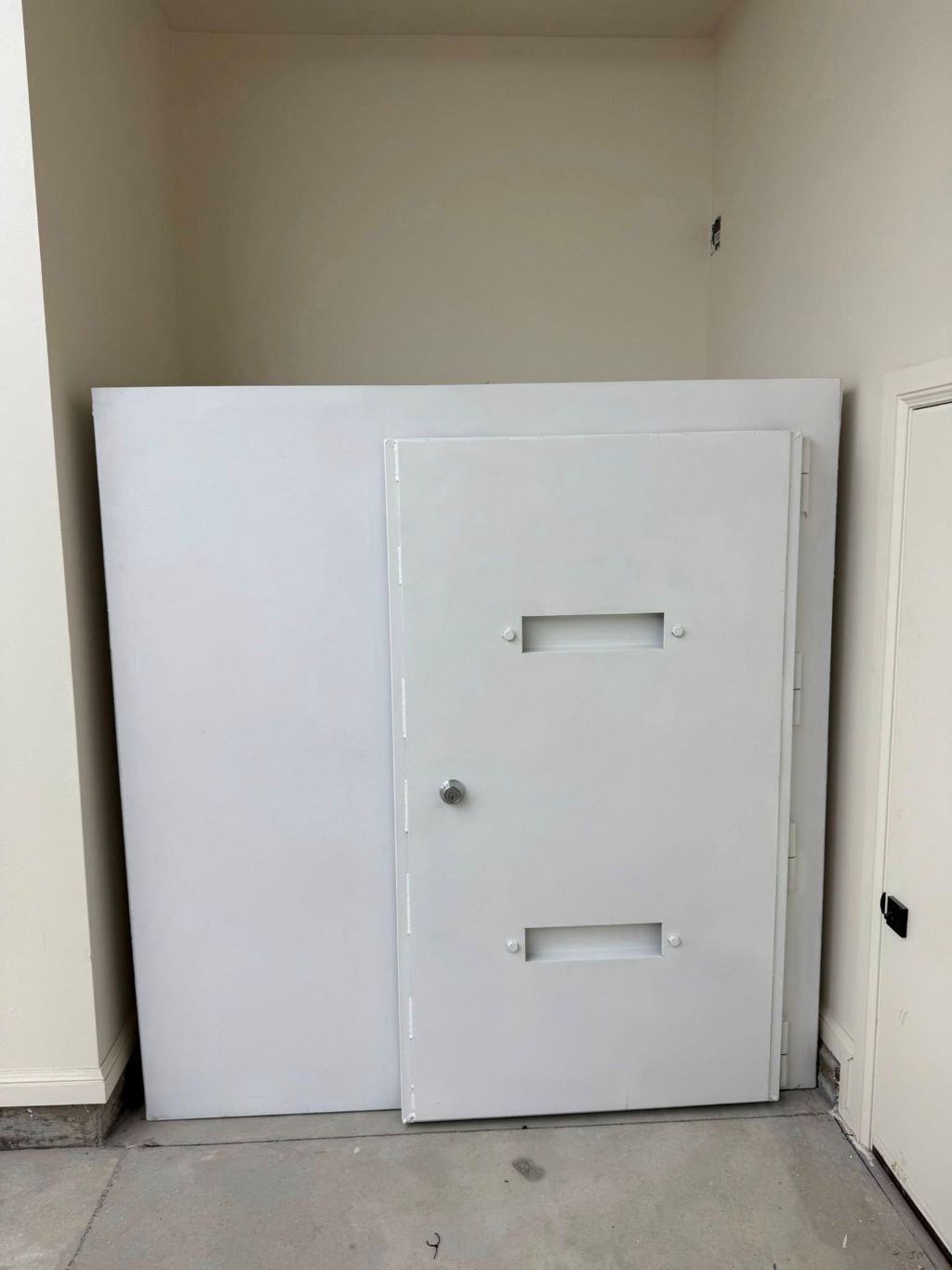 Large white metal security door in a plain hallway nook