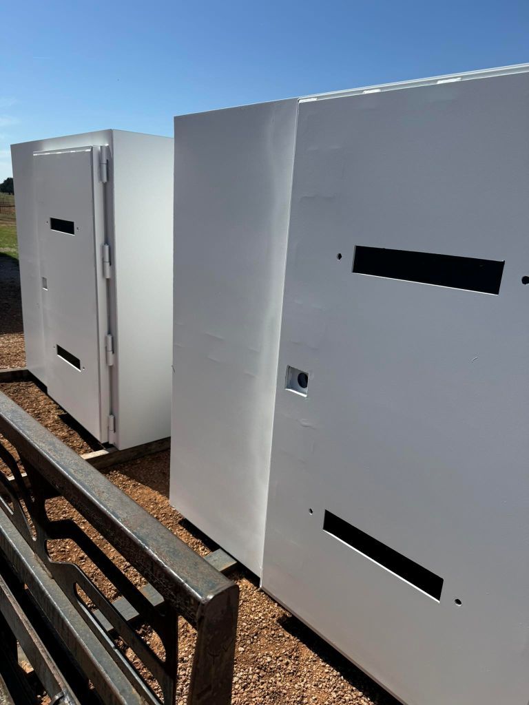 Large white storm shelters outdoors on a gravel lot under a clear blue sky