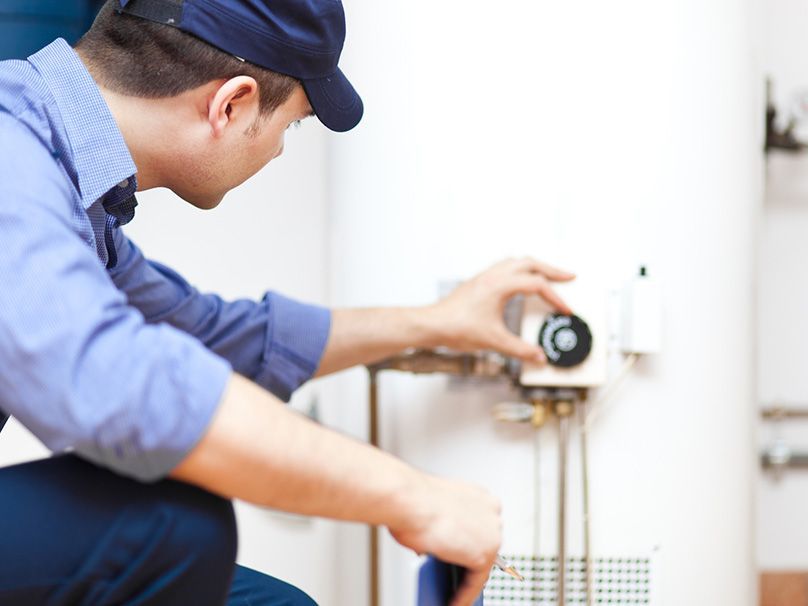 Man Fixing Water Heater - New Castle, PA - Central Heating & Plumbing Man Fixing Water Heater - New Castle, PA - Central Heating & Plumbing