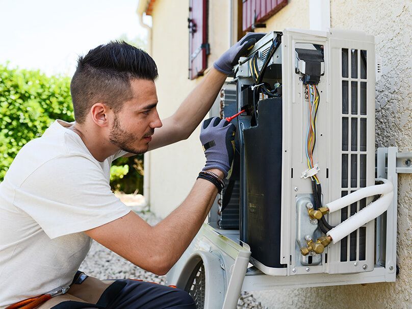 Man Installing Air Condition - New Castle, PA - Central Heating & Plumbing Man Installing Air Condition - New Castle, PA - Central Heating & Plumbing
