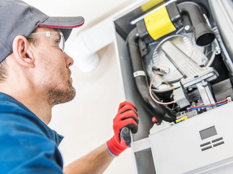 Man Repairing Furnace - New Castle, PA - Central Heating & Plumbing Man Repairing Furnace - New Castle, PA - Central Heating & Plumbing