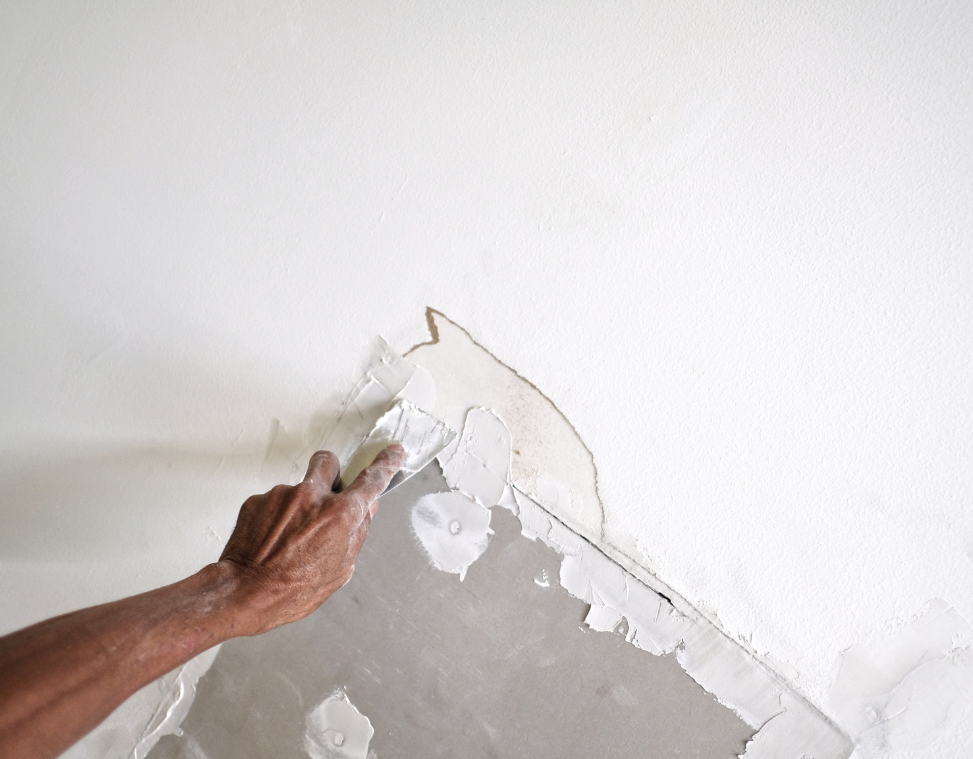 A person is plastering a wall with a drywall knife.