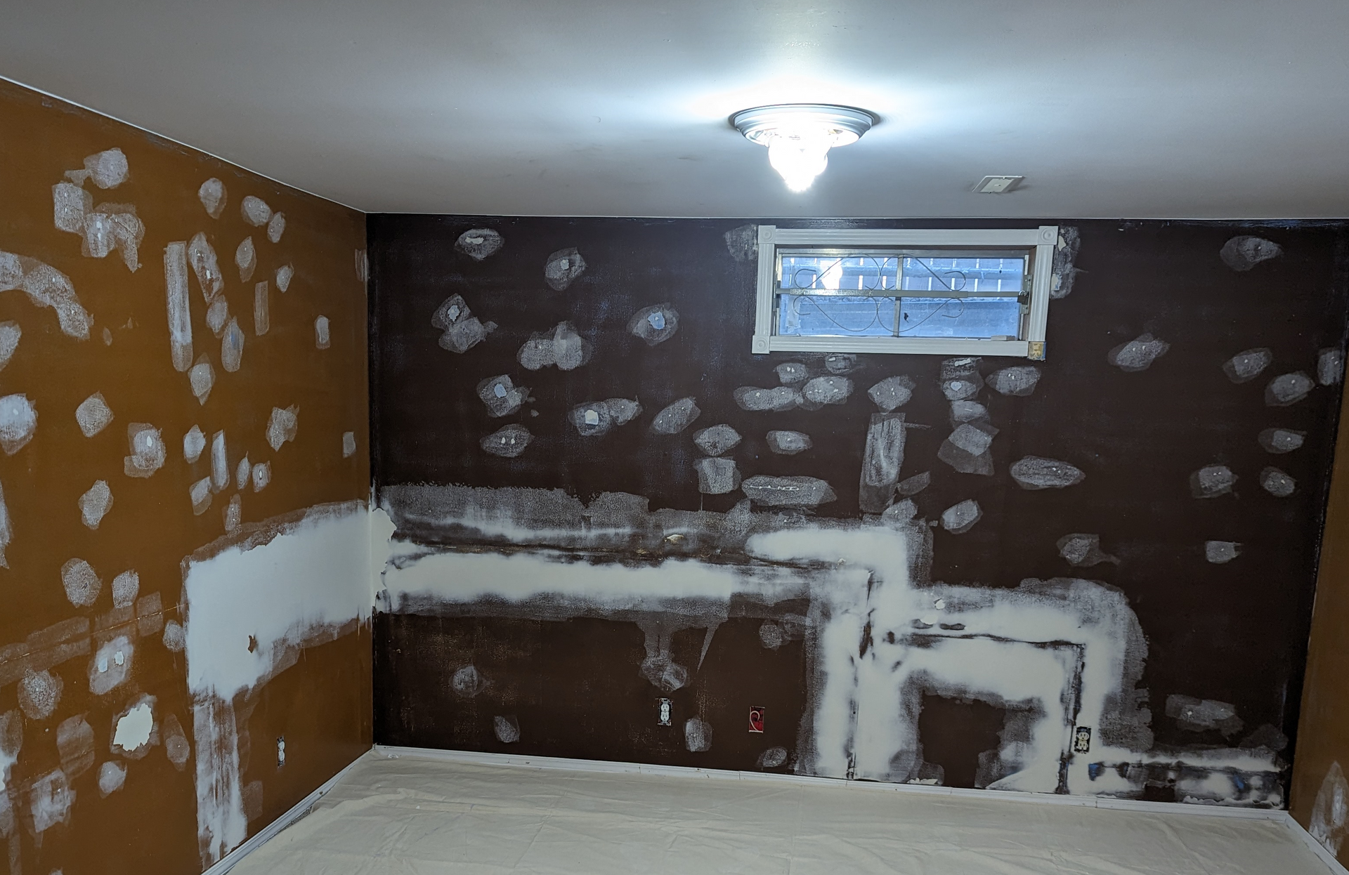 An empty room with brown walls and a window and lots of patches