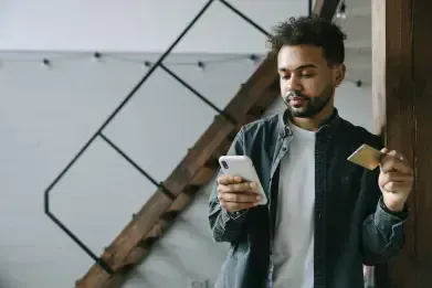 Man holding a phone and coffee in a modern interior with a geometric wall decor