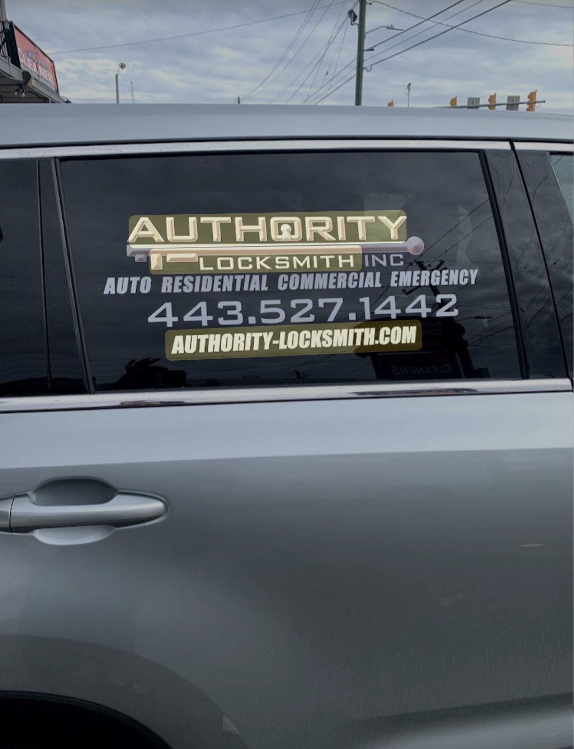 Side window of an Authority Locksmith Inc car with the phone number and website