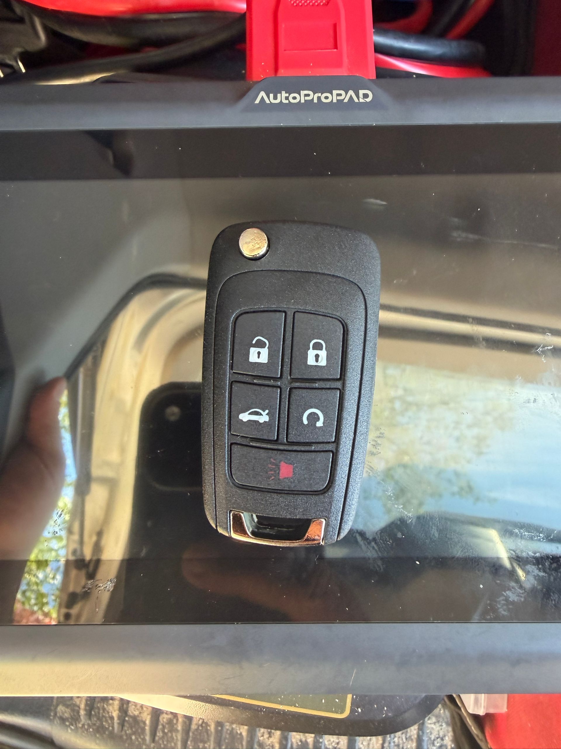 Four-button GM flip key held up by an Authority Locksmith Inc locksmith