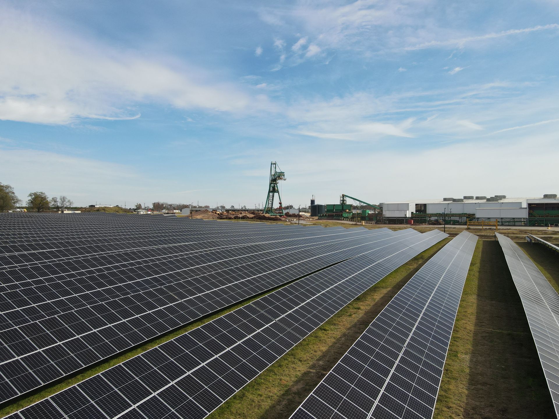 A row of solar panels in a field with a building in the background.
