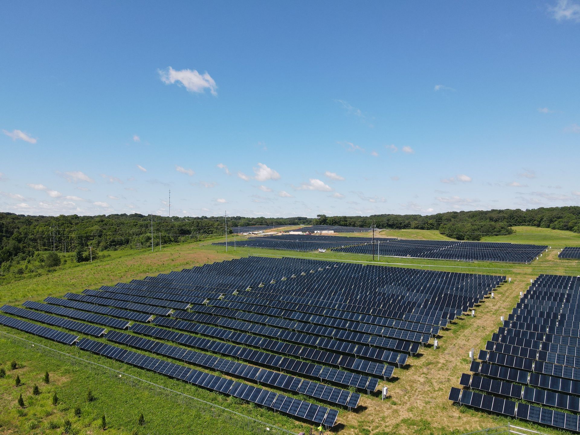 Rows of blue solar panels in a grassy field under a clear blue sky