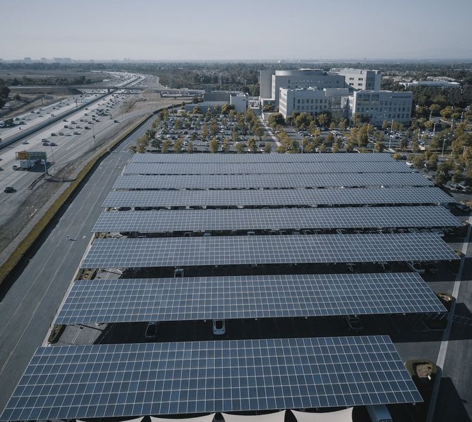 Learn More About Large-Scale Solar Panel Installations An aerial view of a parking lot with lots of solar panels that also act as shading for the lot