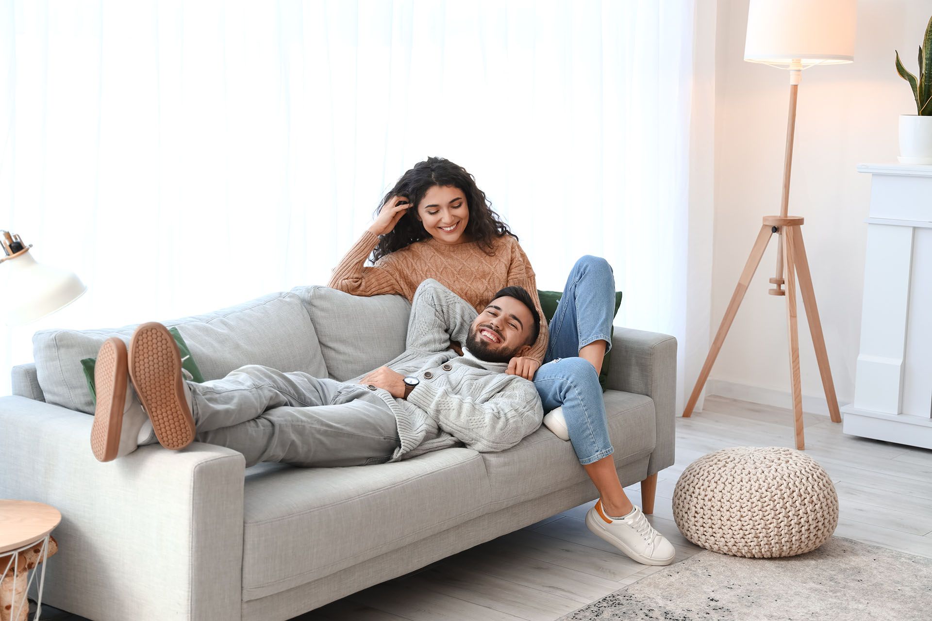 A man and a woman are sitting on a couch in a living room.