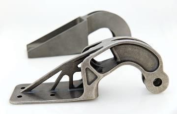 Two gray metal brackets, one with intricate supports, against a white background.