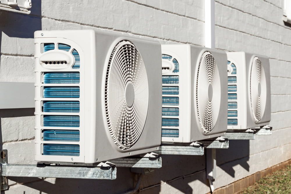 A Row Of Air Conditioners Are Lined Up On The Side Of A Building — Evolution Solar Kingaroy in Murgon, QLD