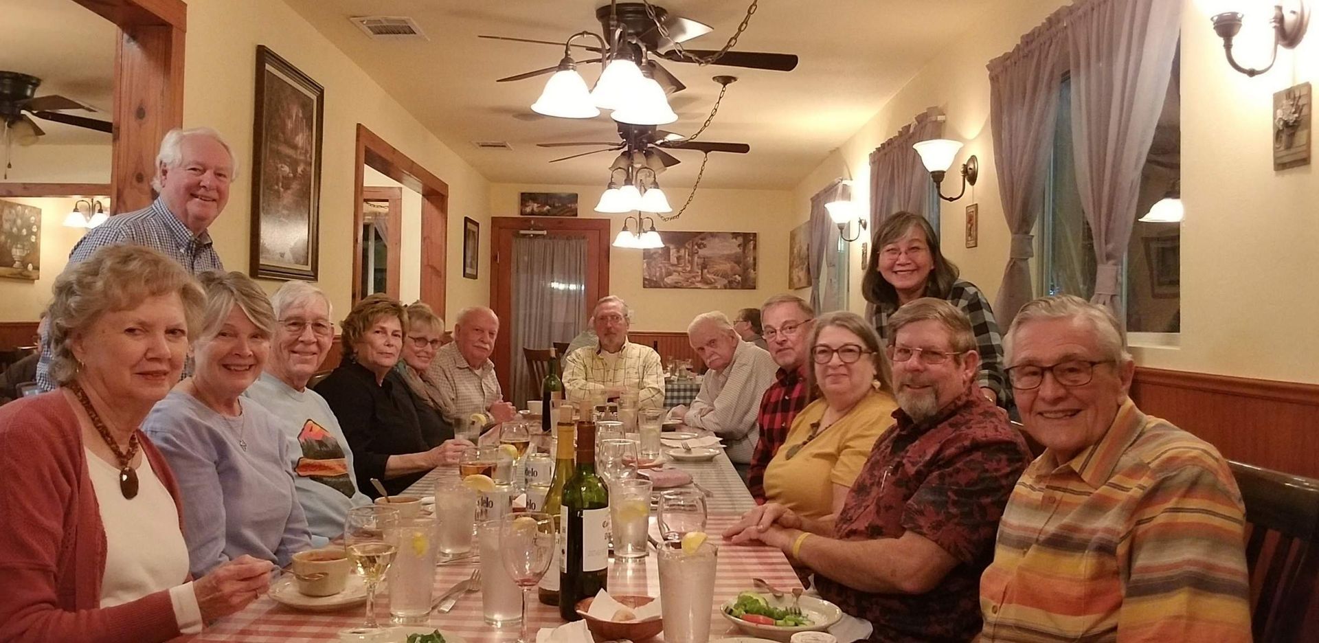 A group of people sitting at a long table in a restaurant. They are smiling.