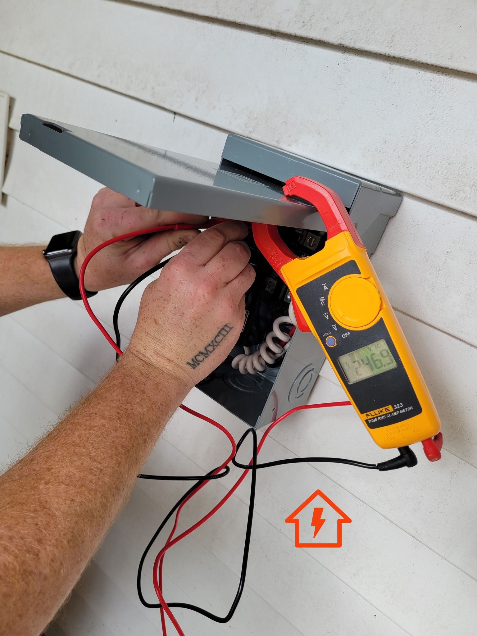 A man is using a clamp meter on a wall.