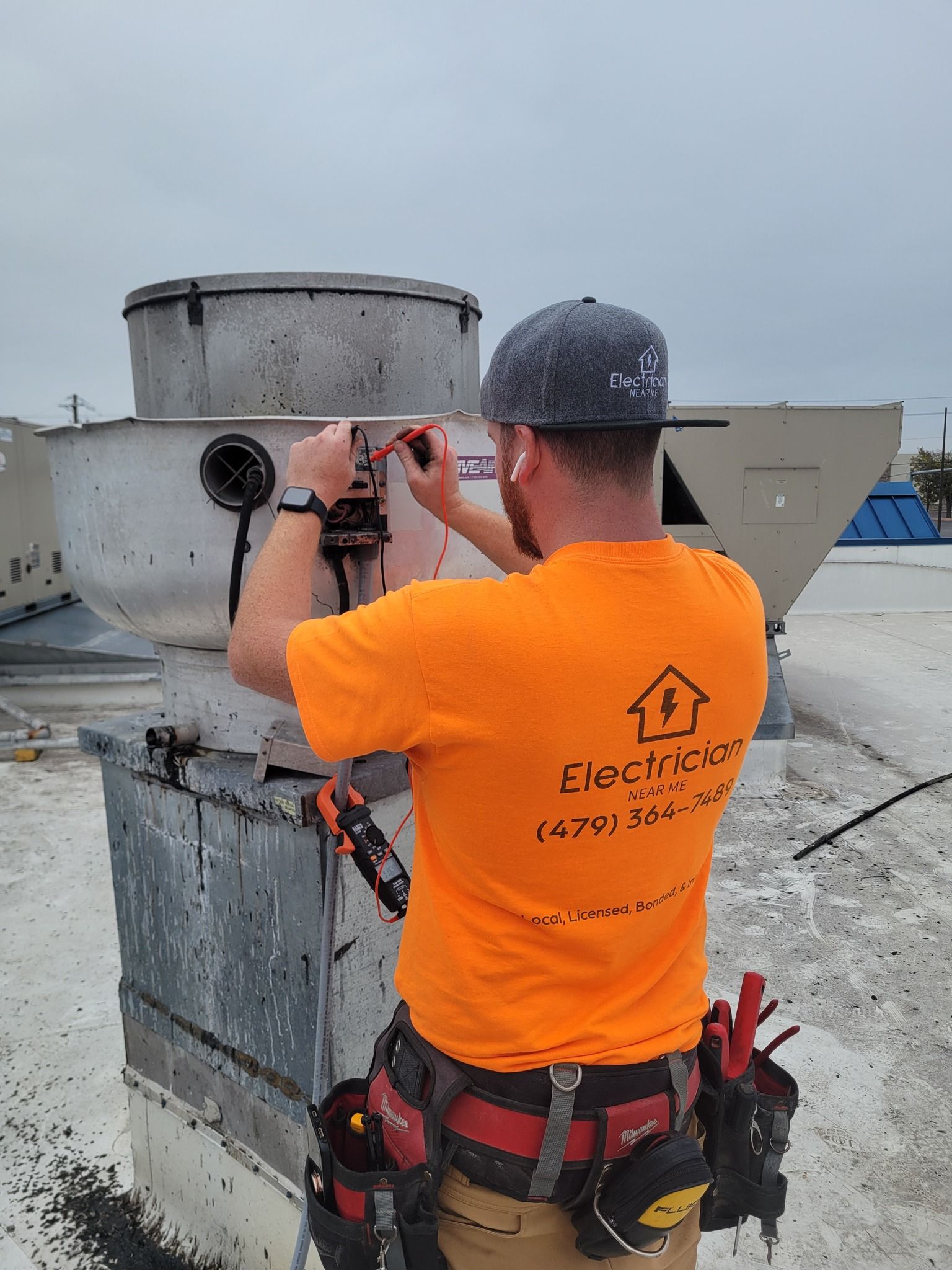 A man in an orange shirt is working on a roof.