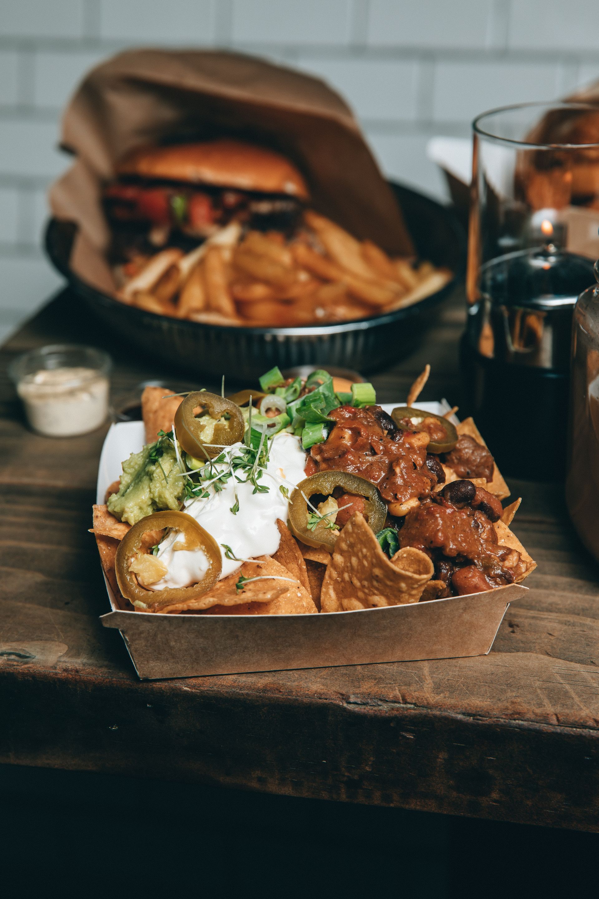 Et brett med nachos med guacamole og rømme på et trebord.