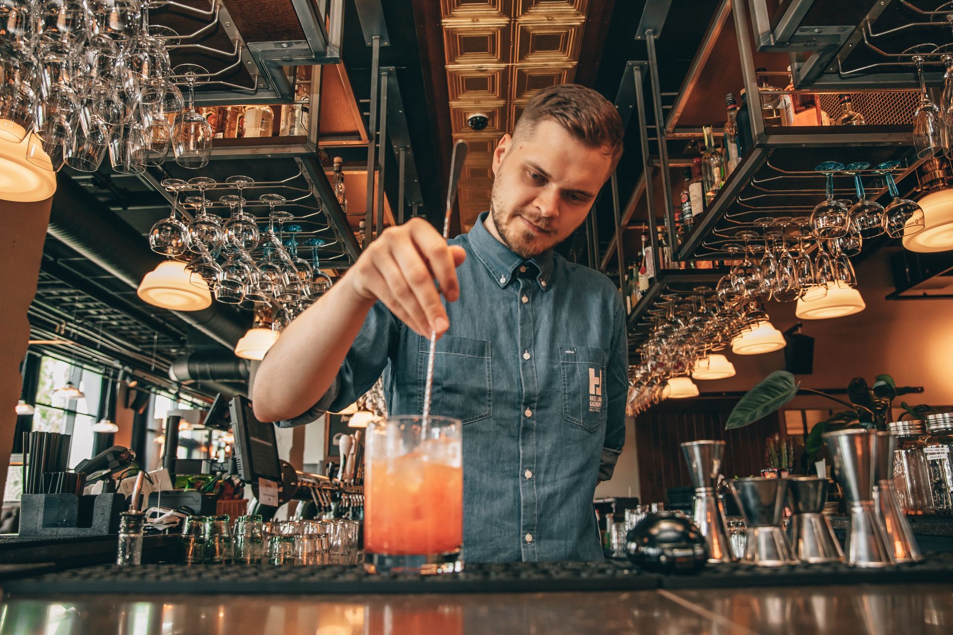 En bartender skjenker en drink i et glass på en bar.