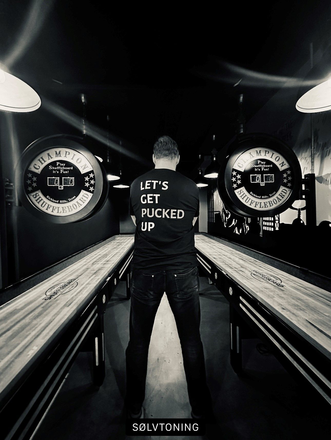 En mann som står mellom to shuffleboards