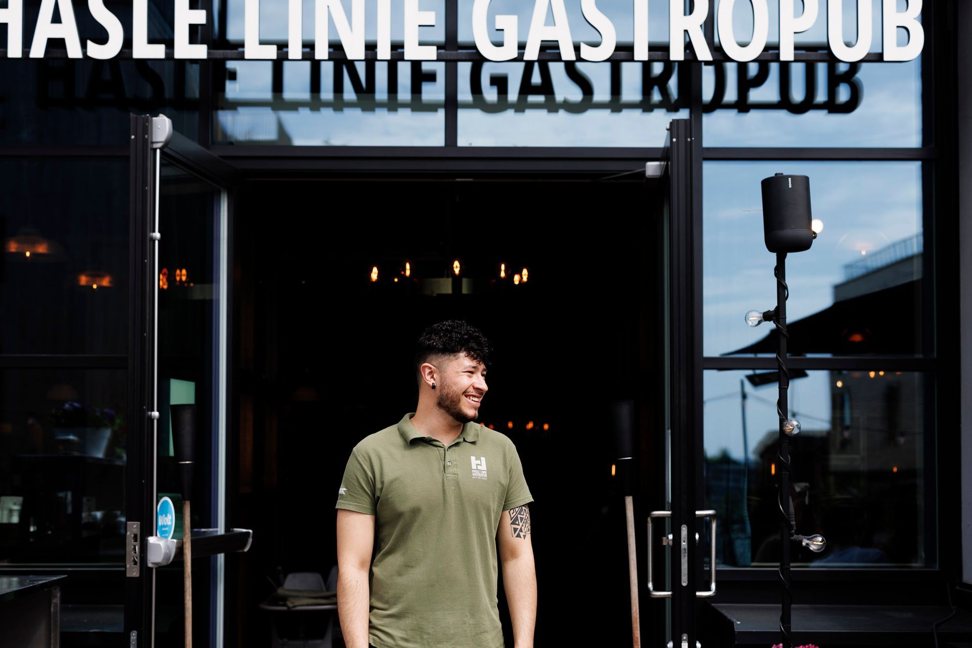 En mann i grønn skjorte står foran en restaurant.