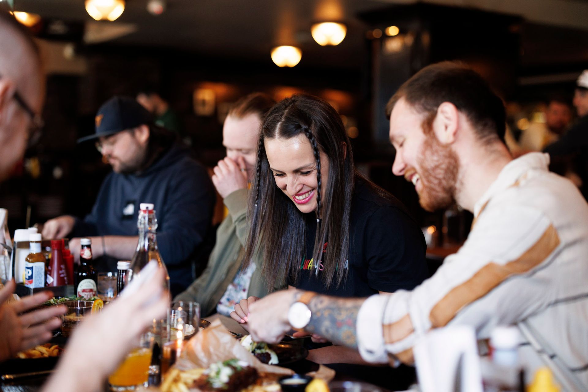 En gruppe mennesker sitter ved et bord på en restaurant og spiser mat.
