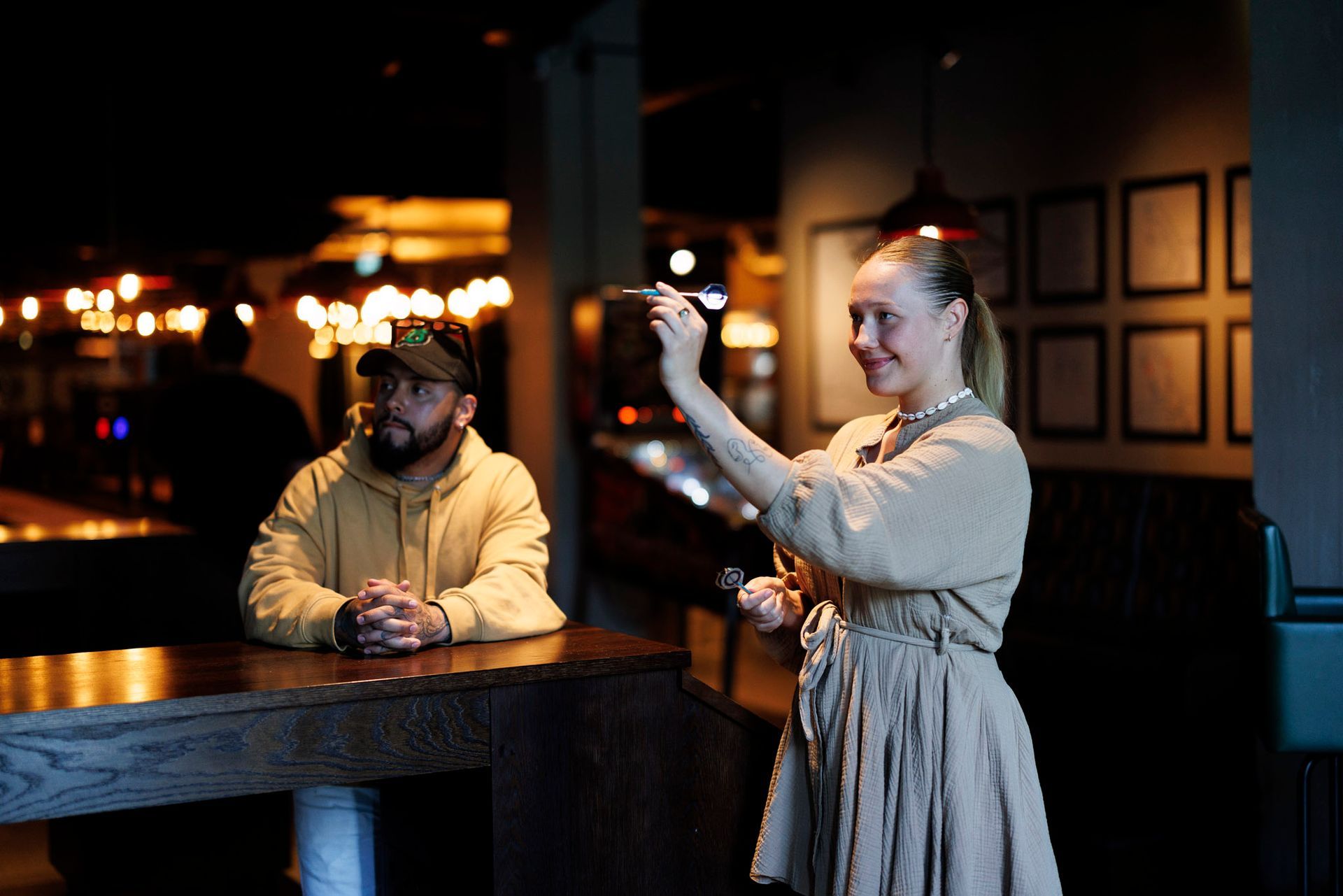 En kvinne tar et bilde av en mann som sitter ved en bar.