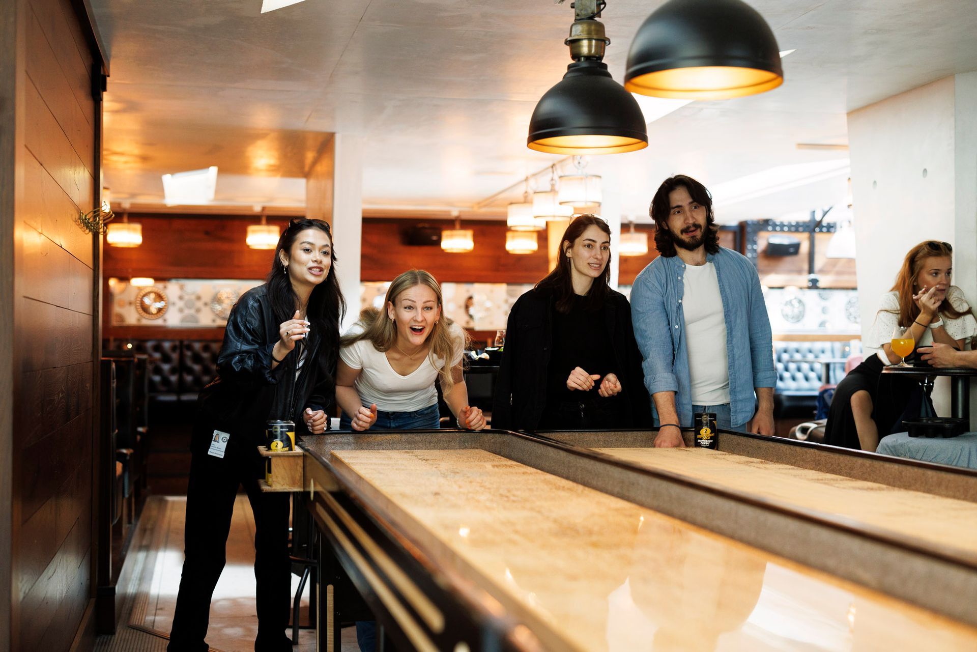 En gruppe mennesker spiller shuffleboard på en restaurant.