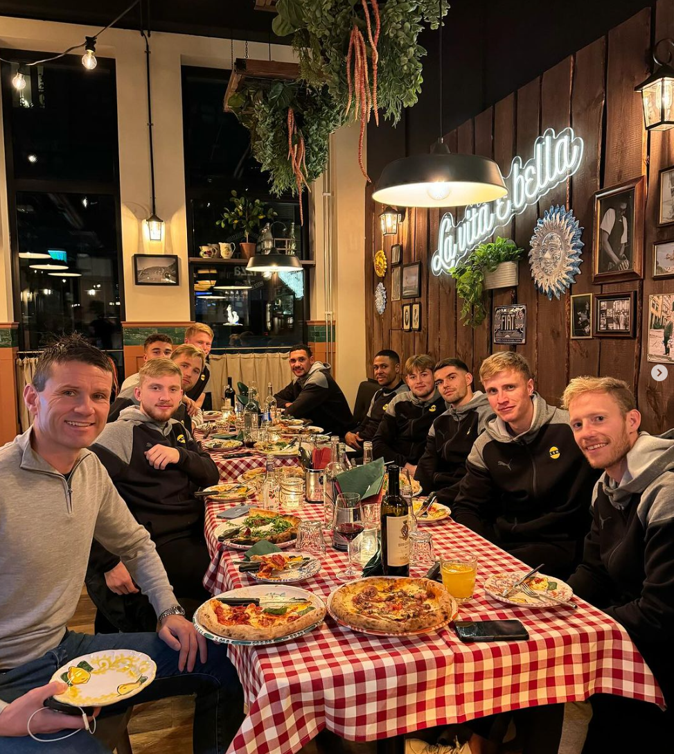 En gruppe mennesker sitter ved et langbord på en restaurant.