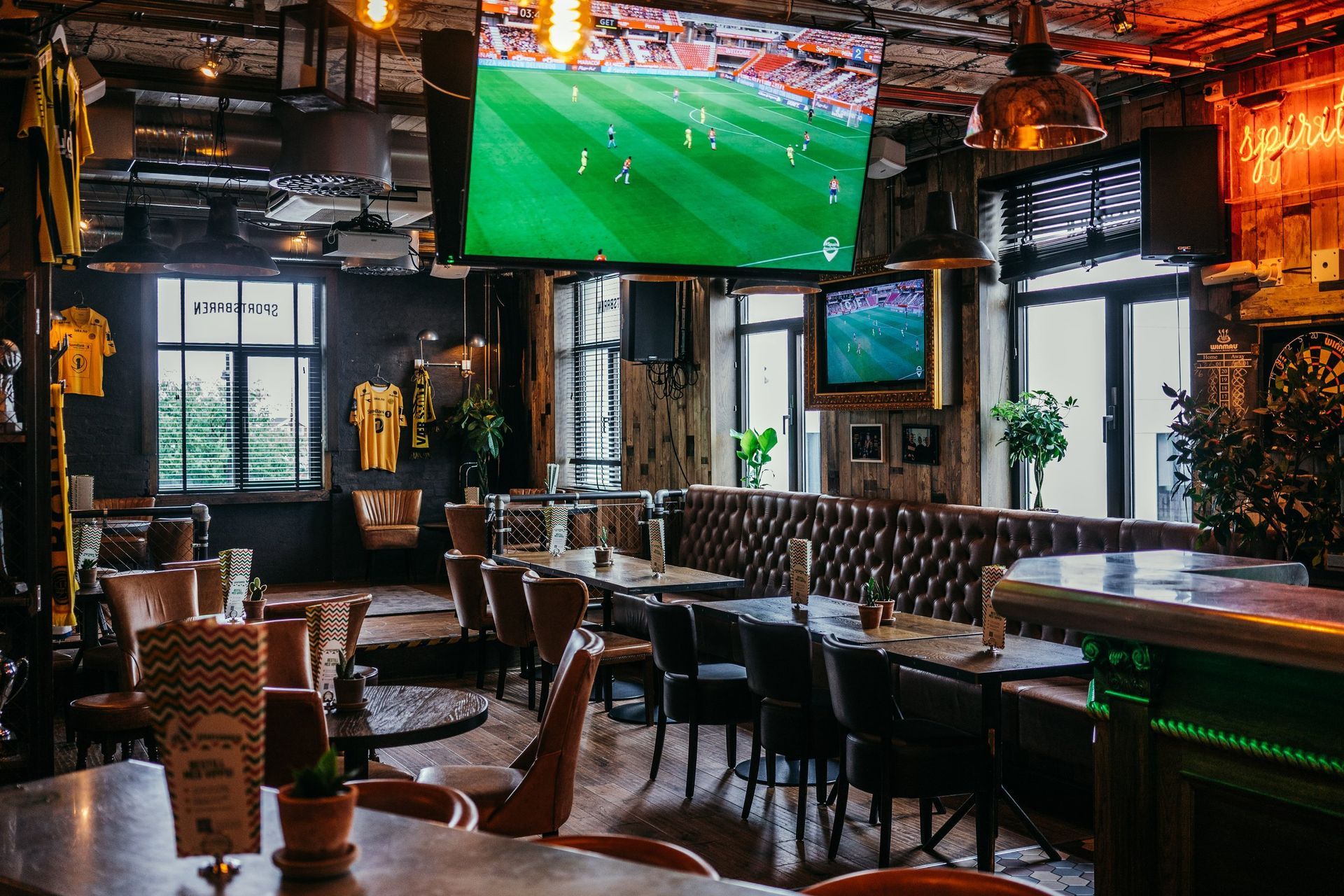 En fotballkamp spilles på en storskjerm på en restaurant.