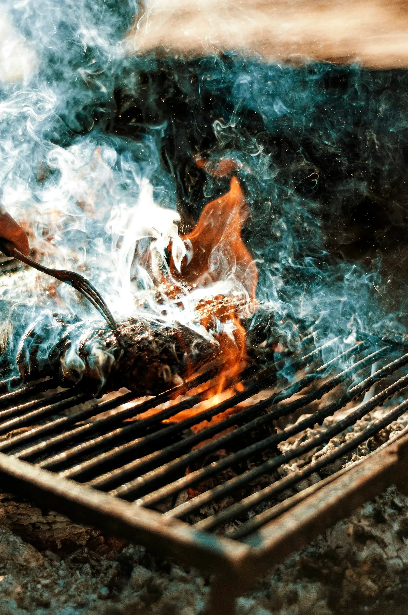 Burger grillet over åpen ild på en metallrist, med stigende røyk.