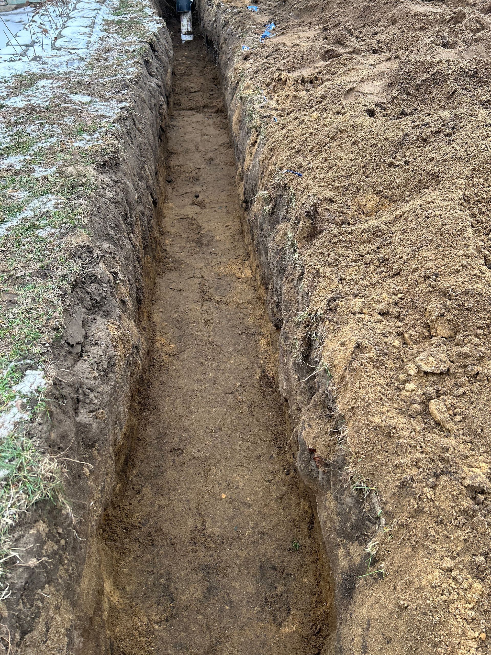 A person is digging a trench in the dirt.