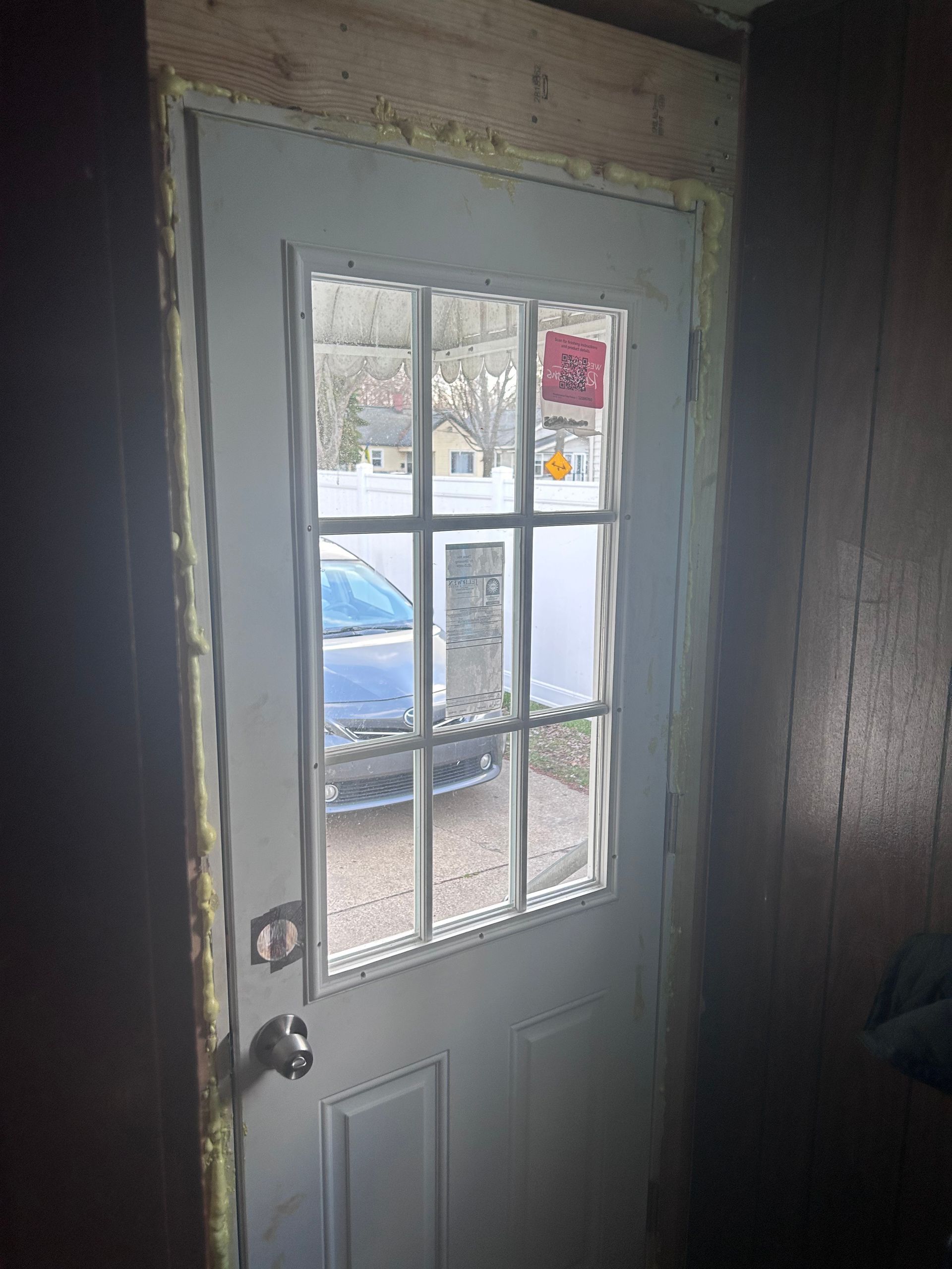 A white door with a window in a dark room.