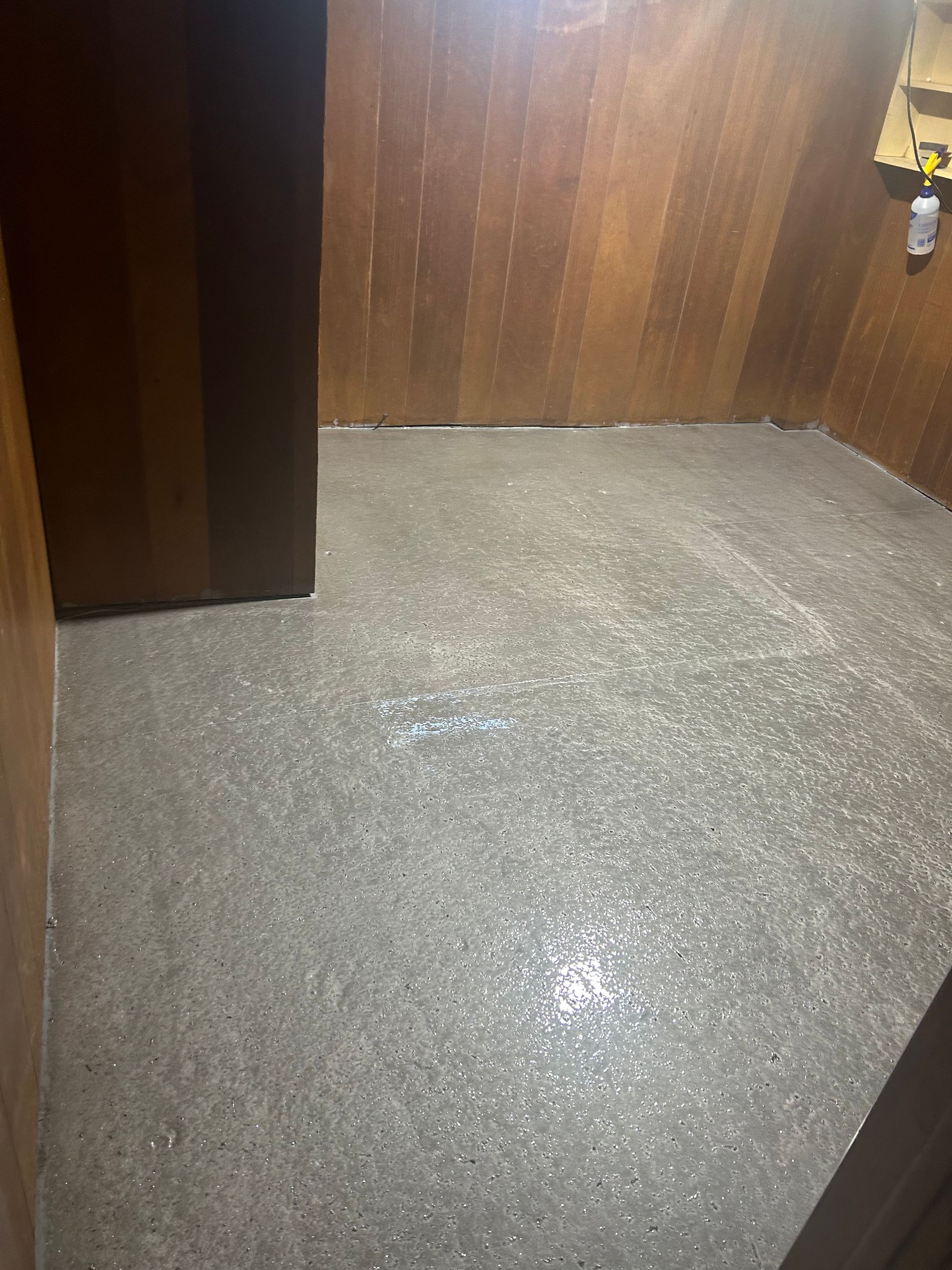 A room with a concrete floor and wooden walls.