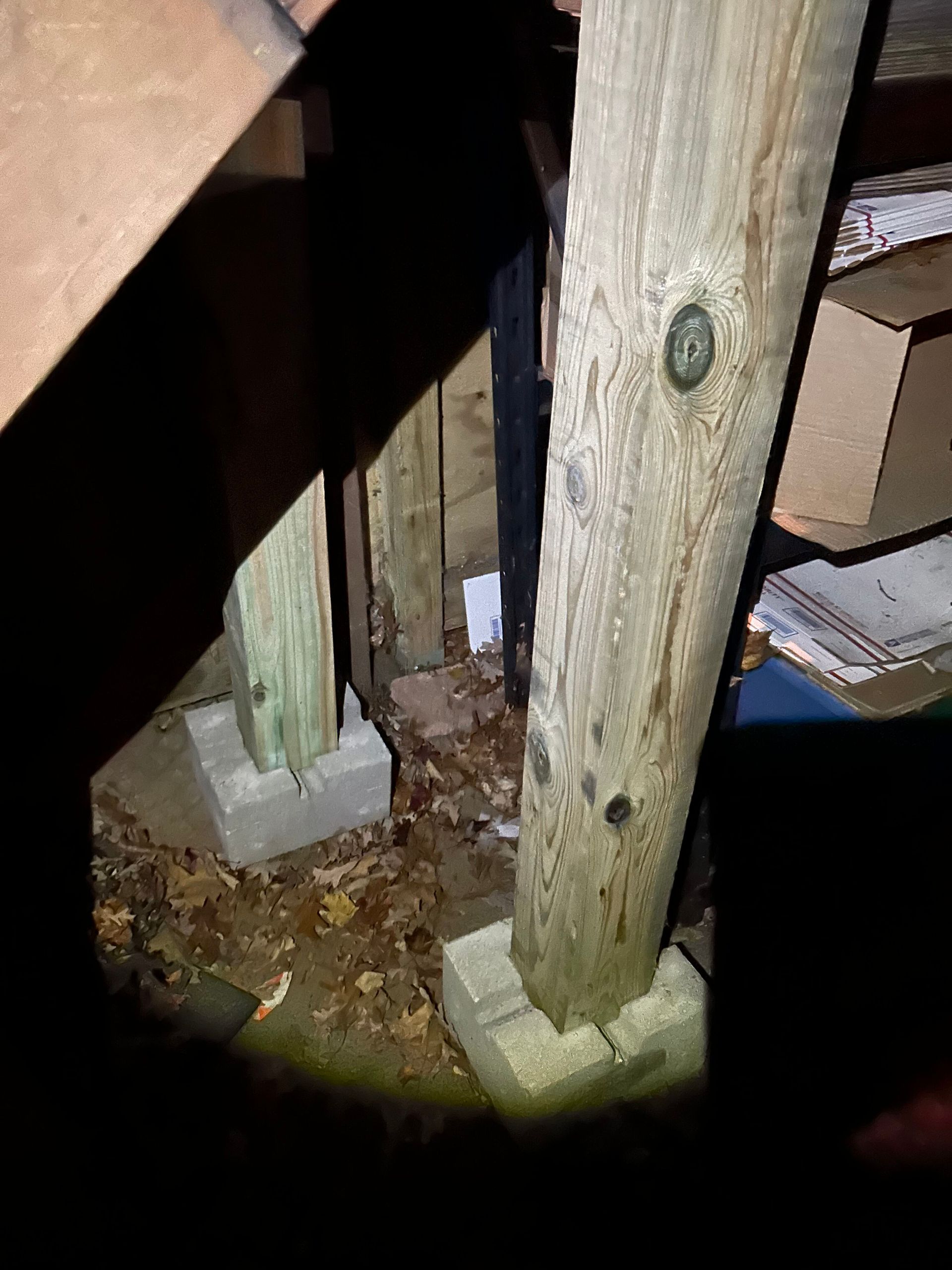 A person is looking through a magnifying glass at a wooden post in an attic.