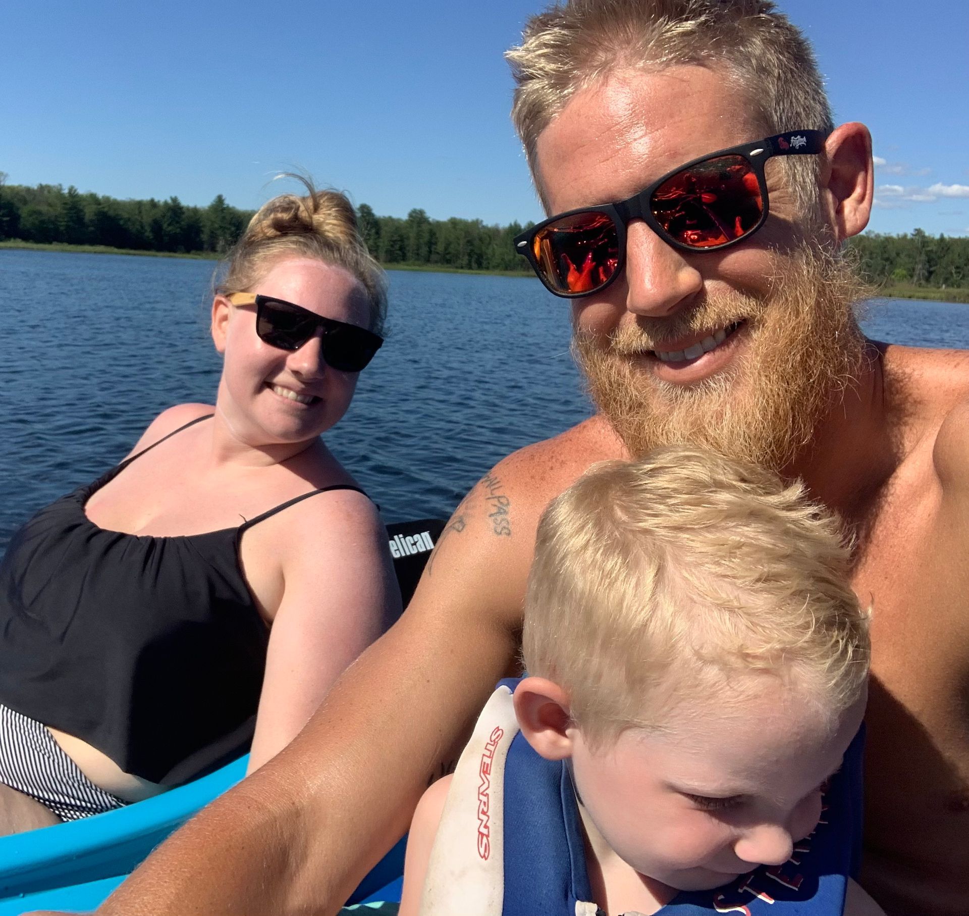 A man wearing sunglasses is holding a child in a life jacket