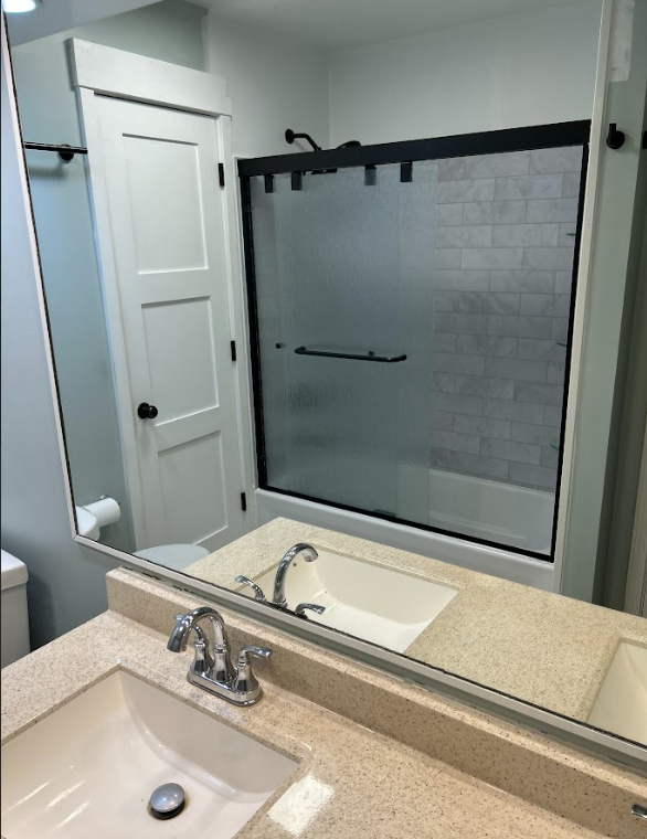 A bathroom with a sink , toilet , shower and mirror