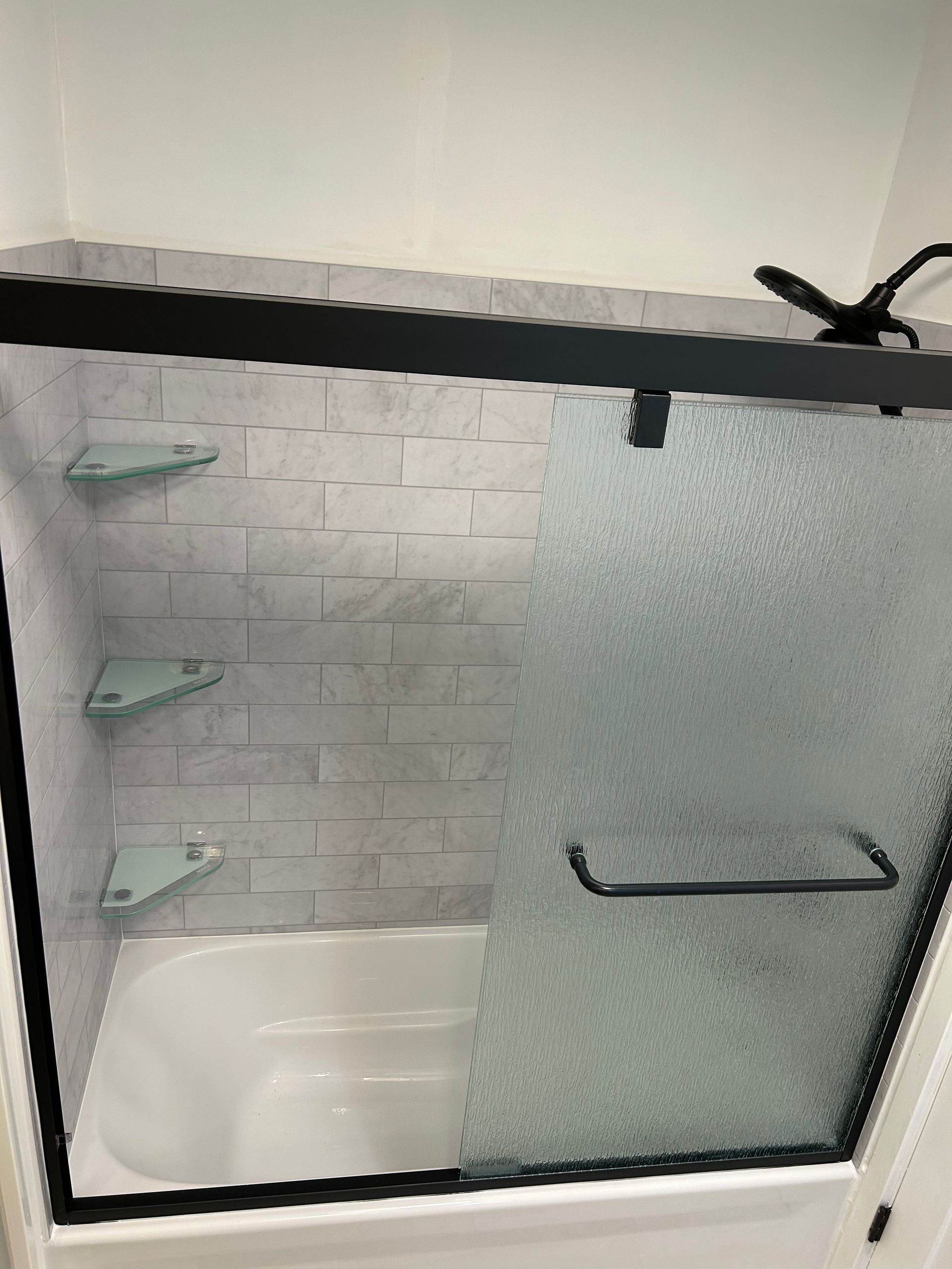 A bathroom with a bathtub and a glass shower door.