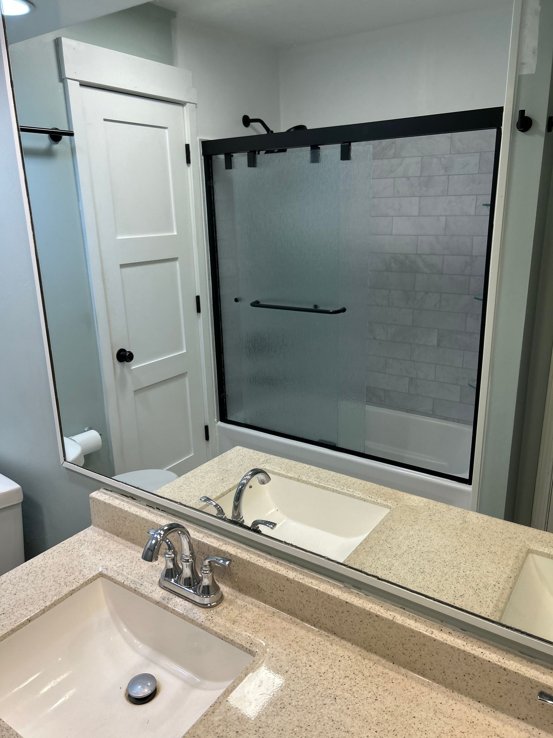 A bathroom with a sink , toilet , shower and mirror.