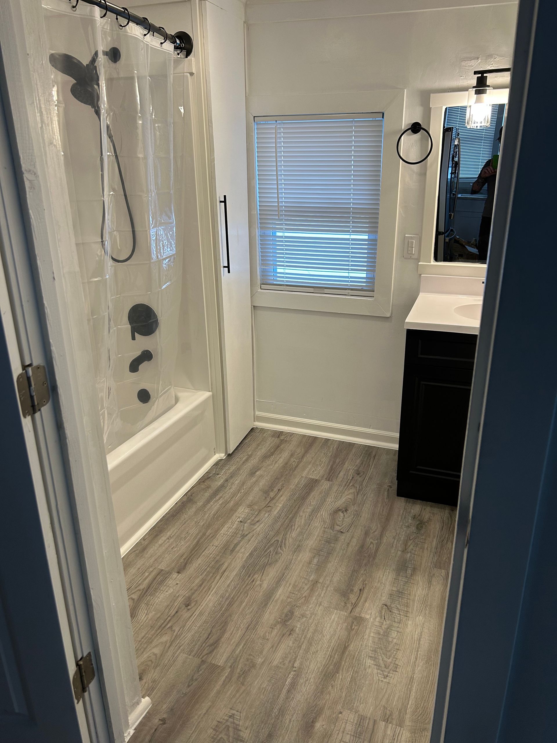 A bathroom with a tub , shower , sink and window.