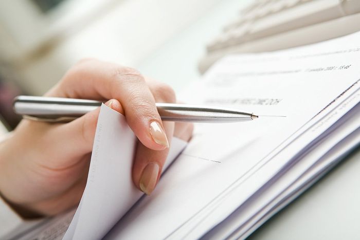 A person is writing on a piece of paper with a pen
