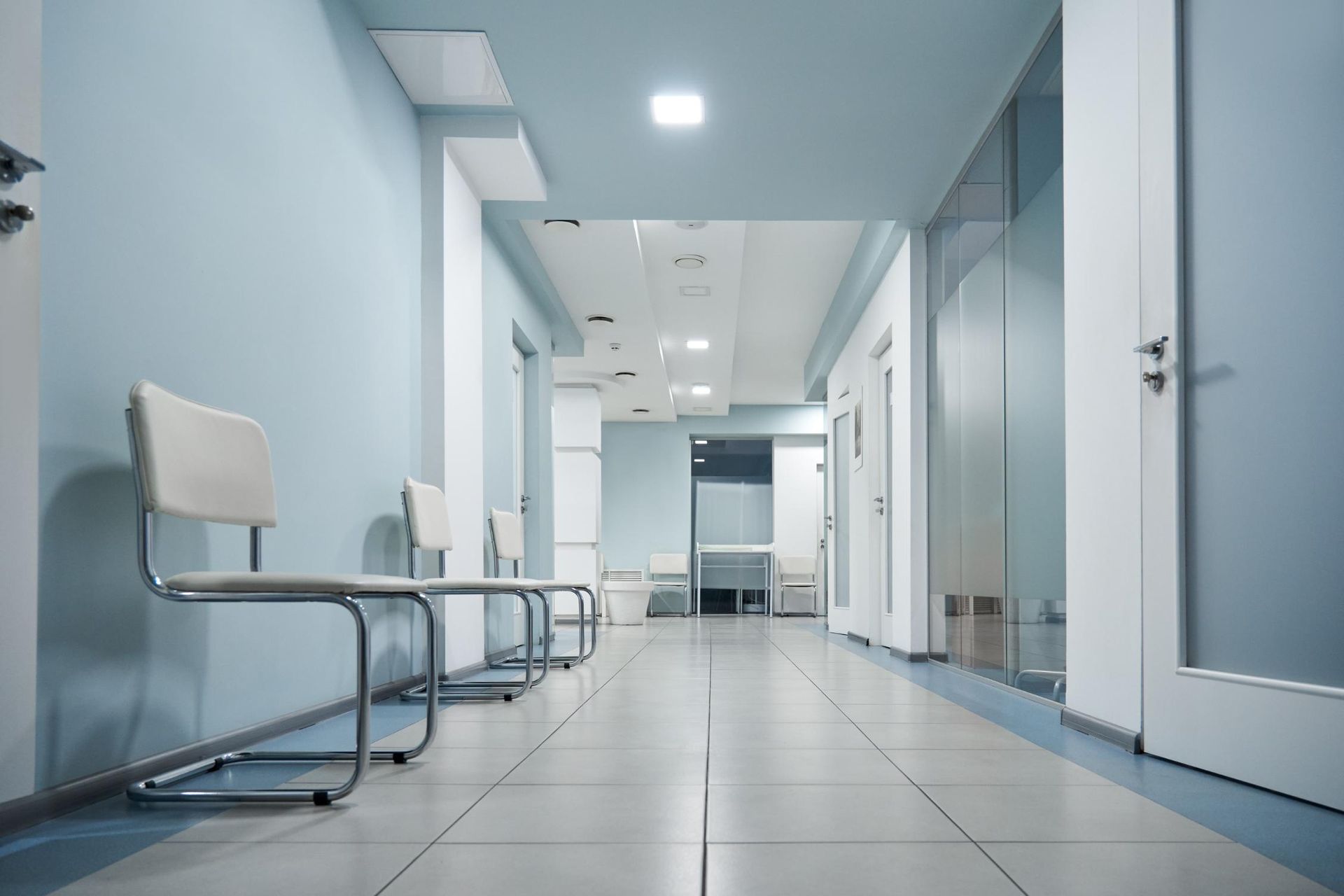 There are a lot of chairs in the hallway of a hospital.