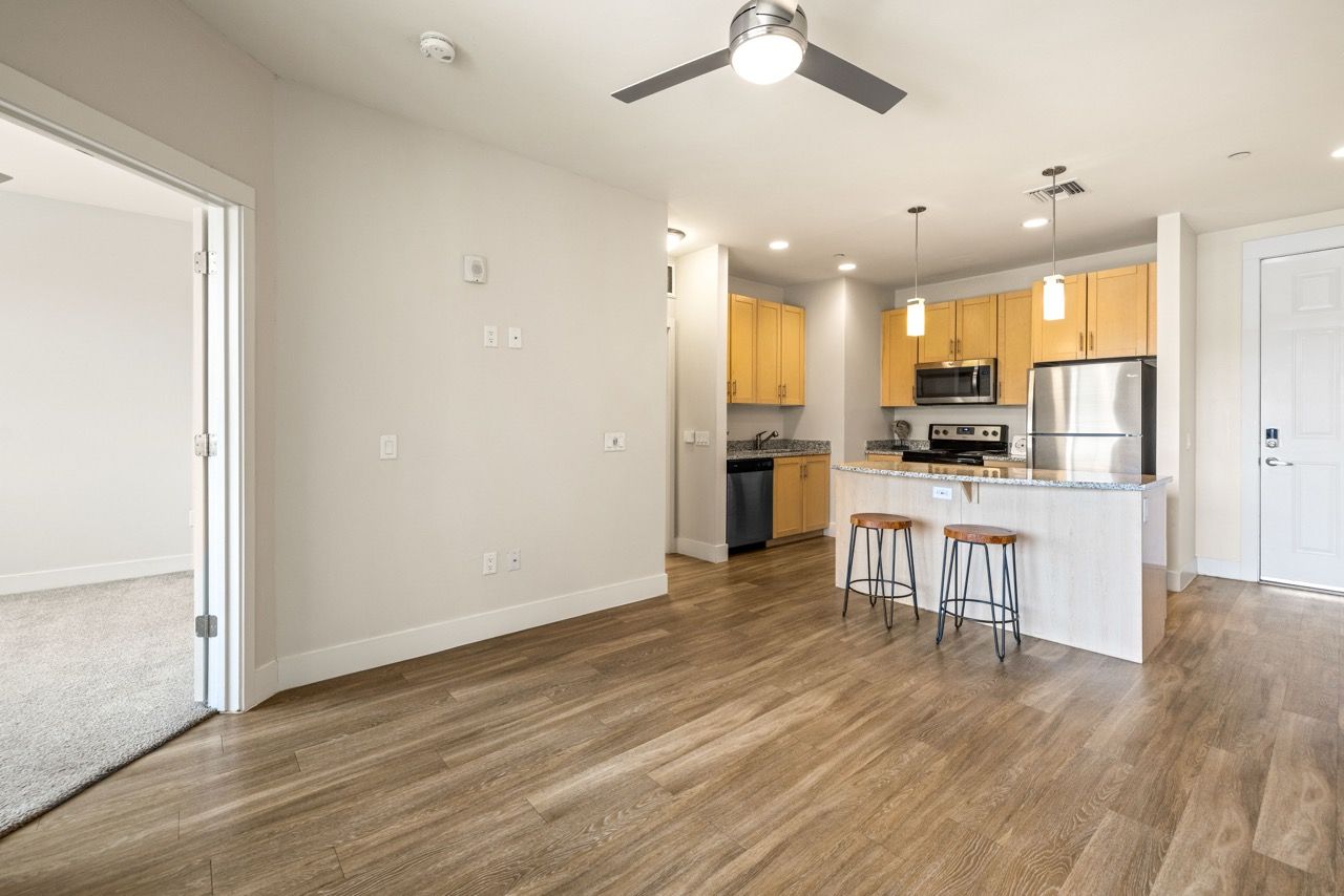Open-concept kitchen and living area with an island, pendant lights, and stainless-steel appliances at Mountain Trail, offering apartments in Flagstaff, AZ.