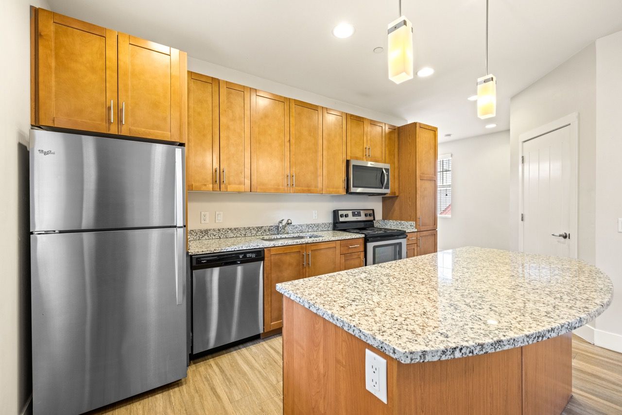 Modern apartment kitchen with granite countertops, stainless steel appliances, and a large island at Mountain Trail, offering apartments for rent in Flagstaff, AZ.